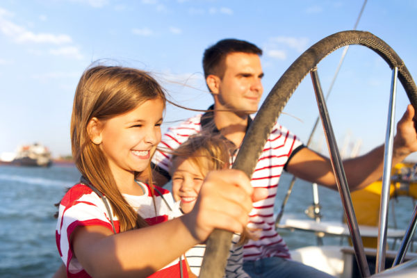 Young father with adorable daughters resting on a big boat